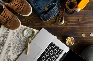 Laptop ile harita ve büyüteç ile eski vintage ahşap masa, blogger çalışma alanı kavramı üzerinde erkek giyimi