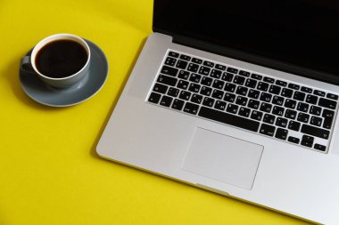 sıcak kahve Kupası parlak zeytin sarı arka planda kadın blogger çalışma alanı kavramı ile gri açık dizüstü 