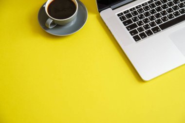 sıcak kahve Kupası parlak zeytin sarı arka planda kadın blogger çalışma alanı kavramı ile gri açık dizüstü 