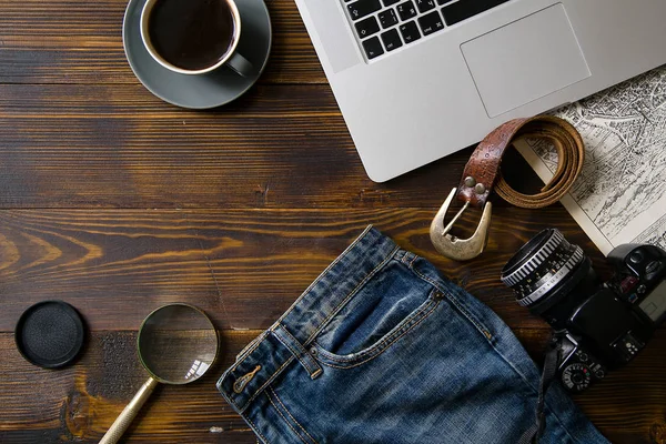 laptop with coffee cup and travel accessories on old vintage wooden table, concept of blogger workspace