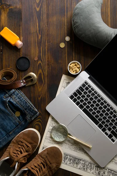 laptop with map and magnifier with male clothes on old vintage wooden table, concept of blogger workspace