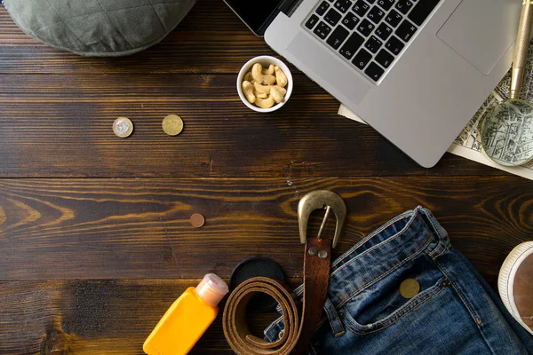 laptop with map and magnifier with male clothes on old vintage wooden table, concept of blogger workspace