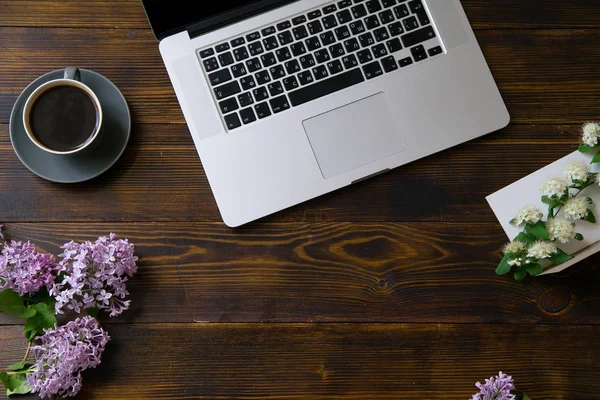 laptop and flowers with coffee cup on vintage wooden table