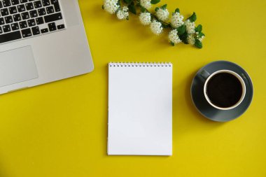 sıcak kahve fincanı ve çiçek ve parlak zeytin sarı arka plan kavramı kadın blogger çalışma alanının üstünde defter ile şube ile dizüstü bilgisayar 