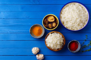 kase pişmiş pirinç Yasemin ve sırılsıklam shiitake mantar mavi ahşap arka plan üzerinde renkli baharatlar ile