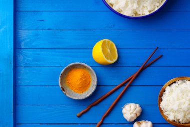 kase pişmiş pirinç Yasemin ve çubuk mavi ahşap arka plan üzerinde renkli baharat