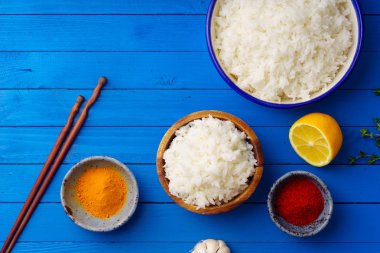 kase pişmiş pirinç Yasemin ve çubuk mavi ahşap arka plan üzerinde renkli baharat