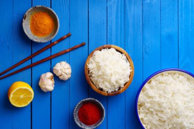 kase pişmiş pirinç Yasemin ve çubuk mavi ahşap arka plan üzerinde renkli baharat