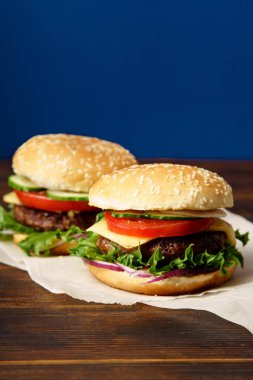 Mutfak parşömen kağıt sayfalarının klasik Burger ile mavi arka plan karşı ahşap masa yılları arasında görev yapmıştır