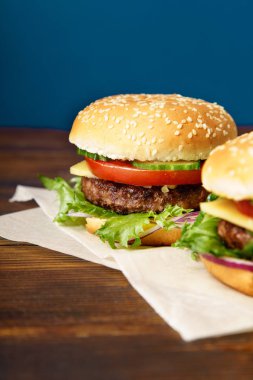 Mutfak parşömen kağıt sayfalarının klasik Burger ile mavi arka plan karşı ahşap masa yılları arasında görev yapmıştır