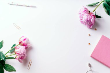 Pembe piyonlar ve beyaz arka plan üzerinde romantik kavramı izole kulaklık ile defter ile kadınsı çalışma alanı