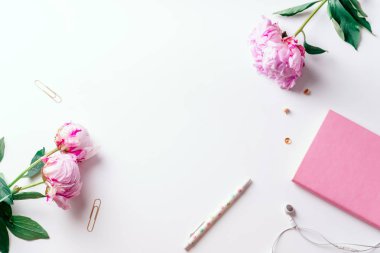 Pembe piyonlar ve beyaz arka plan üzerinde romantik kavramı izole kulaklık ile defter ile kadınsı çalışma alanı