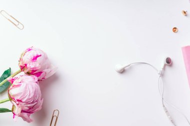 Pembe piyonlar ve beyaz arka plan üzerinde izole kulaklık ile defter ile kadınsı çalışma alanı
