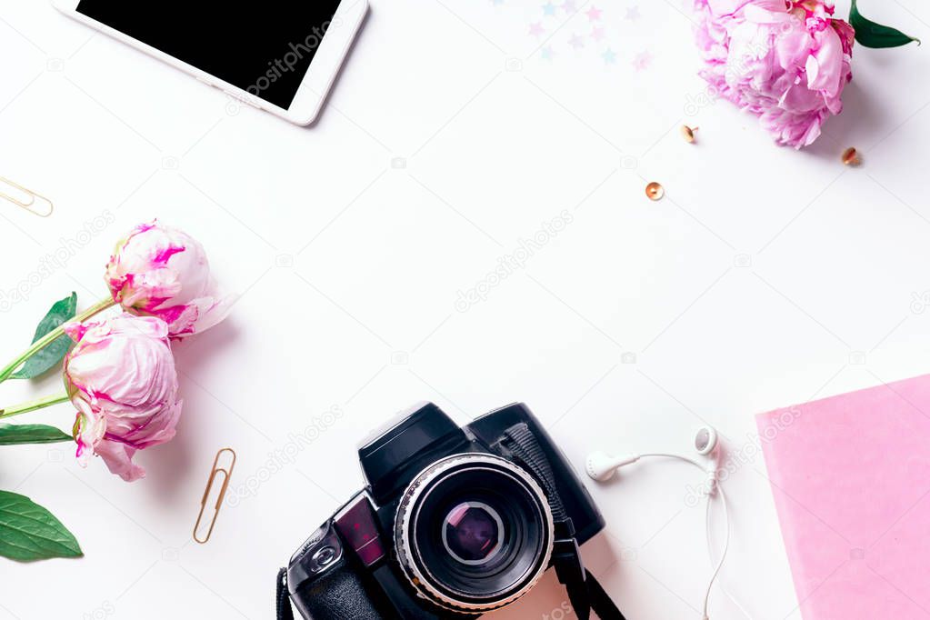Feminine workspace with pink peons and phone with camera isolated on white background