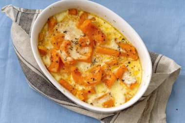 Kavrulmuş bir kase kabak pişmiş ve ağır krema parmesan peyniri ile kekik ve beyaz şarap ile mavi arka plan üzerinde 