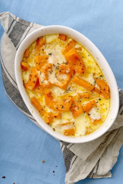 Kavrulmuş bir kase kabak pişmiş ve ağır krema parmesan peyniri ile kekik ve beyaz şarap ile mavi arka plan üzerinde 