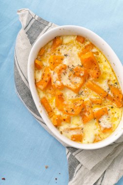 Kavrulmuş bir kase kabak pişmiş ve ağır krema parmesan peyniri ile kekik ve beyaz şarap ile mavi arka plan üzerinde 