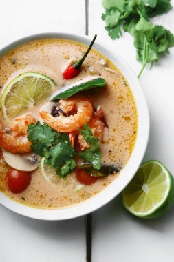 geleneksel Tay çorbası tom yum karides ve mantarlı beyaz rustik ahşap arka plan taze limon dilimleri ile servis ile kase