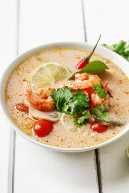 geleneksel Tay çorbası tom yum karides ve mantarlı beyaz rustik ahşap arka plan taze limon dilimleri ile servis ile kase