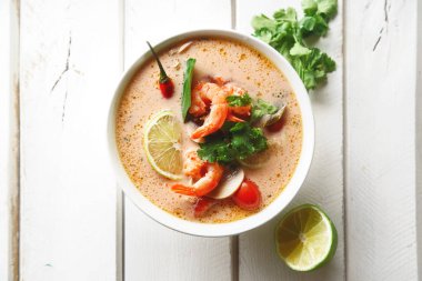 geleneksel Tay çorbası tom yum karides ve mantarlı beyaz rustik ahşap arka plan taze limon dilimleri ile servis ile kase