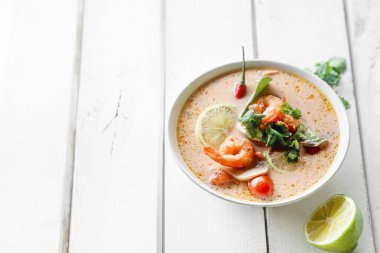 geleneksel Tay çorbası tom yum karides ve mantarlı beyaz rustik ahşap arka plan taze limon dilimleri ile servis ile kase