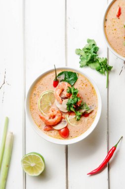 kase ile geleneksel Tay çorbası tom yum karides ve mantar ile beyaz rustik ahşap arka plan taze limon dilimleri ile servis