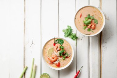 kase ile geleneksel Tay çorbası tom yum karides ve mantar ile beyaz rustik ahşap arka plan taze limon dilimleri ile servis