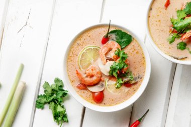 kase ile geleneksel Tay çorbası tom yum karides ve mantar ile beyaz rustik ahşap arka plan taze limon dilimleri ile servis