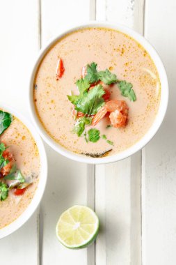 kase ile geleneksel Tay çorbası tom yum karides ve mantar ile beyaz rustik ahşap arka plan taze limon dilimleri ile servis
