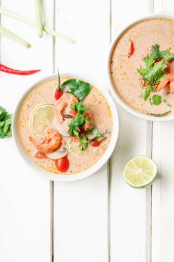 kase ile geleneksel Tay çorbası tom yum karides ve mantar ile beyaz rustik ahşap arka plan taze limon dilimleri ile servis