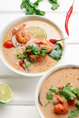 kase ile geleneksel Tay çorbası tom yum karides ve mantar ile beyaz rustik ahşap arka plan taze limon dilimleri ile servis