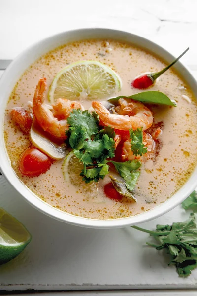 geleneksel Tay çorbası tom yum karides ve mantarlı beyaz rustik ahşap arka plan taze limon dilimleri ile servis ile kase