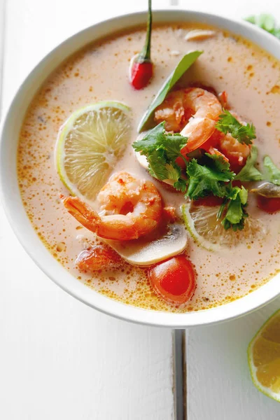 geleneksel Tay çorbası tom yum karides ve mantarlı beyaz rustik ahşap arka plan taze limon dilimleri ile servis ile kase