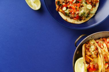 plaka ve tava chili con carne ile Meksika tacos ve rendelenmiş peynir ile tatlı patates ile mavi arka plan üzerinde servis