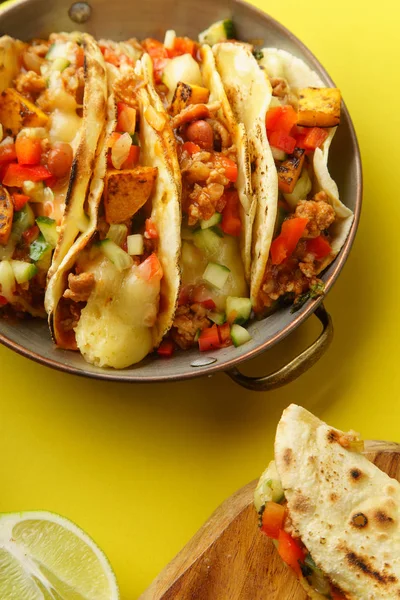 mexican tacos with chili, sweet potatoes and grated cheese served on yellow background