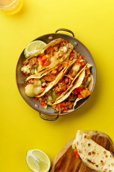 Top view of mexican tacos with chili, sweet potatoes and grated cheese served on blue background