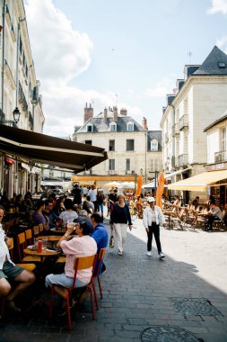 TOURS, FRANCE - AUGUST 14, 2018: street view with traditional french buildings and people resting in restaurants with lovely summer atmosphere clipart