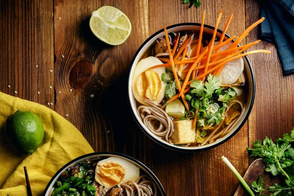 Shiitake mantar, kızarmış tofu, havuç, lahana, pırasa ve ahşap masa üzerinde kireç ile vejetaryen ramen