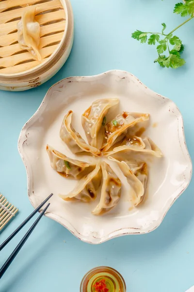 饺子饺子 鸭煮在竹蒸笼与酱油和芝麻种子板上的蓝色背景下 顶部视图 — 图库照片