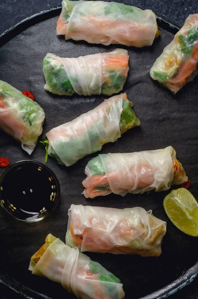 Vegetarian spring rolls with tofu and marinated carrot with daikon and cilantro on stone plate and dark background, Top view