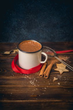 Kırmızı kurdela ile kupa ve süzgeç gingerbread çerezleri ve ahşap zemin, kış içecek konsepti üzerine tarçın ile sıcak çikolata