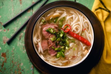 sığır eti ve rustik ahşap masa üzerinde taze kişniş ile geleneksel Vietnam Pho Bo çorbası