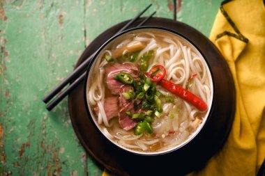 sığır eti ve rustik ahşap masa üzerinde taze kişniş ile geleneksel Vietnam Pho Bo çorbası