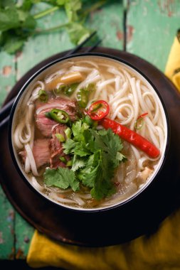 sığır eti ve rustik ahşap masa üzerinde taze kişniş ile geleneksel Vietnam Pho Bo çorbası