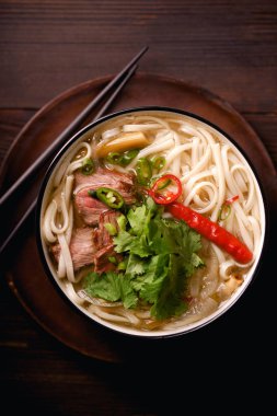 sığır eti ve koyu ahşap zemin üzerine taze kişniş ile geleneksel Vietnam Pho Bo çorba ile tepsi