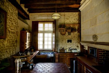 POITIERS, FRANCE - AUGUST 4 , 2018: Kitchen interior at french chateau with vintage fireplace and wooden ceiling with old-fashioned utensils clipart