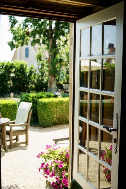 Opened french vintage glass door at the chateau with view at summer patio clipart