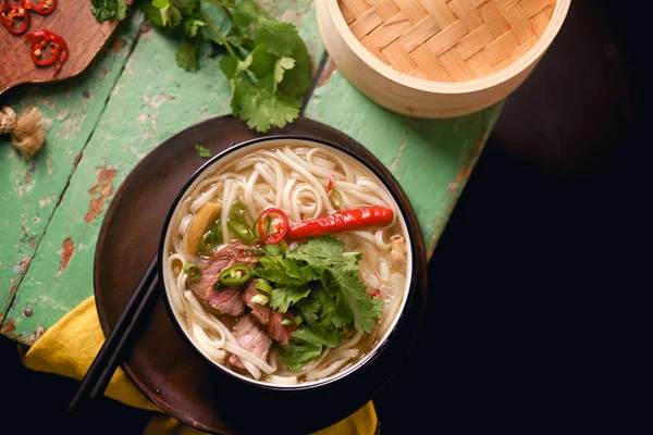 伝統的なベトナム Pho スープ牛肉と素朴な木製のテーブルの上のボウルに新鮮なコリアンダー — ストック写真