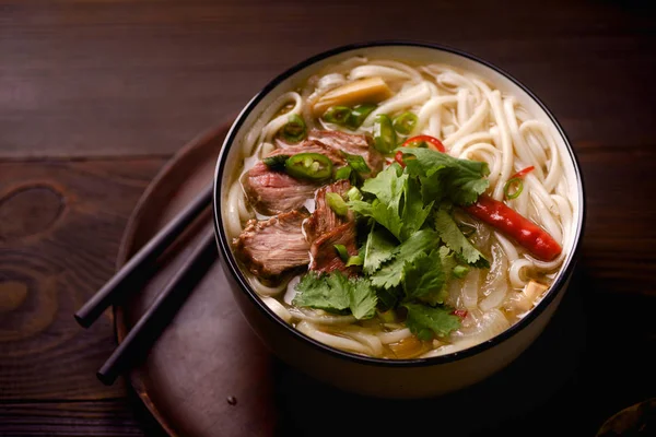 伝統的なベトナム Pho スープ牛肉と暗い背景の木の新鮮なコリアンダーのボウルとトレイ — ストック写真