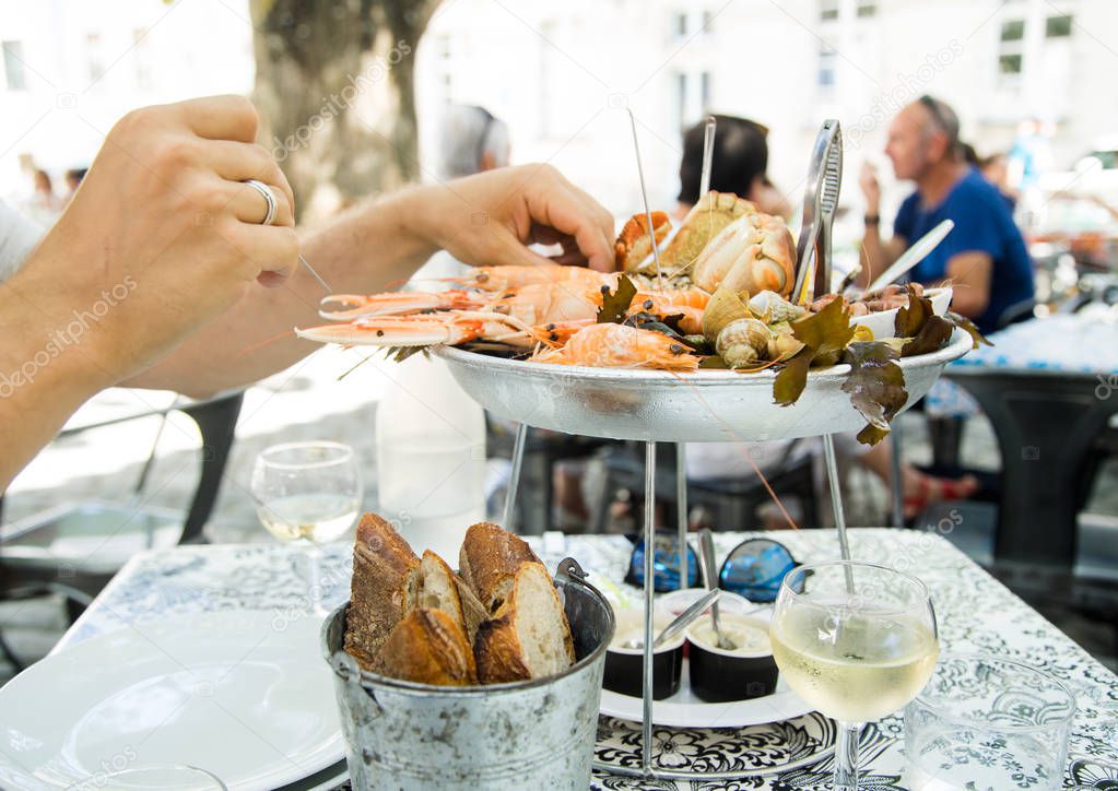 woman eating fresh assorted seafood from plate in french summer restaurant 